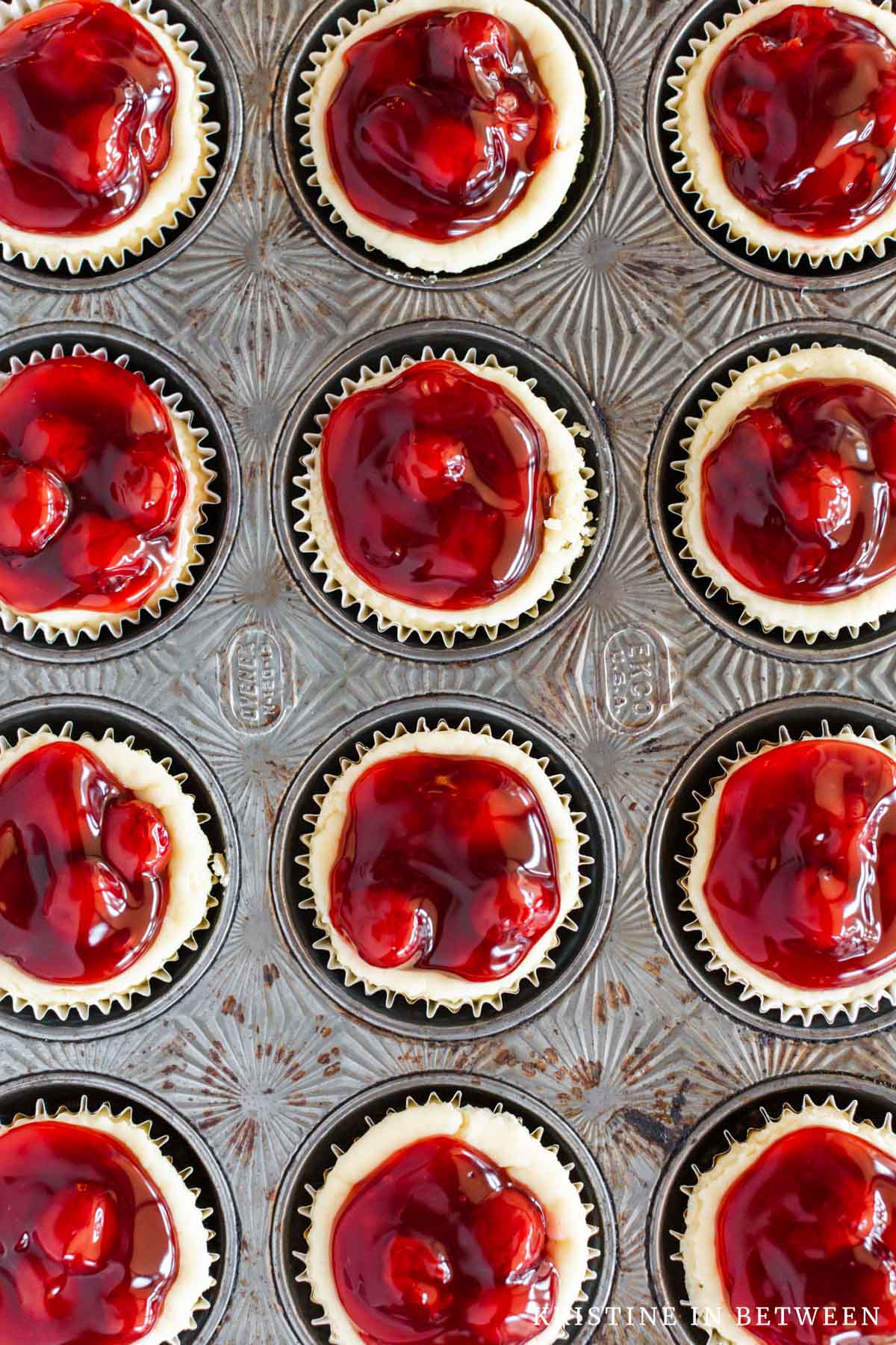 A closeup of cherry tarts in an antique muffin tin.