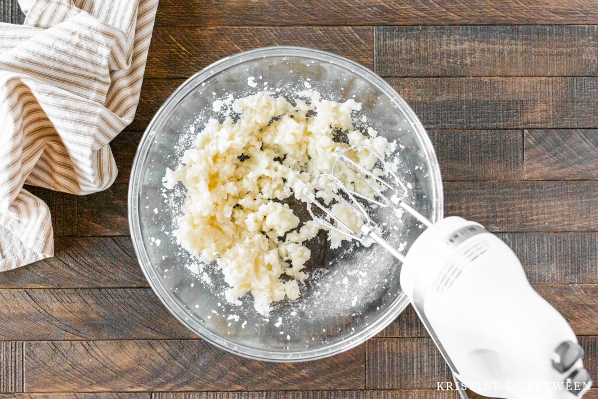 Butter and sugar creamed together with a mixer sitting in the bowl.