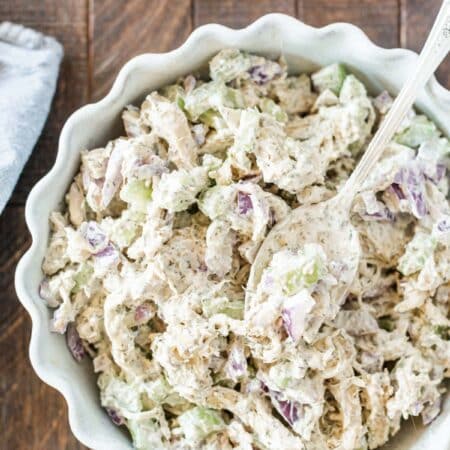 Chicken salad in a bowl with a spoon on top.