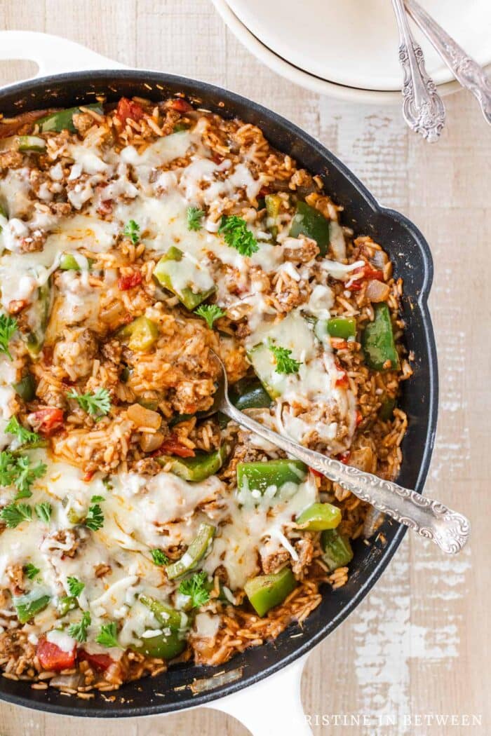 A pan of cooked inside out stuffed peppers with a serving spoon in the center.