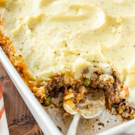 A pan of shepherd's pie with a spoonful removed and a spoon in the pan.