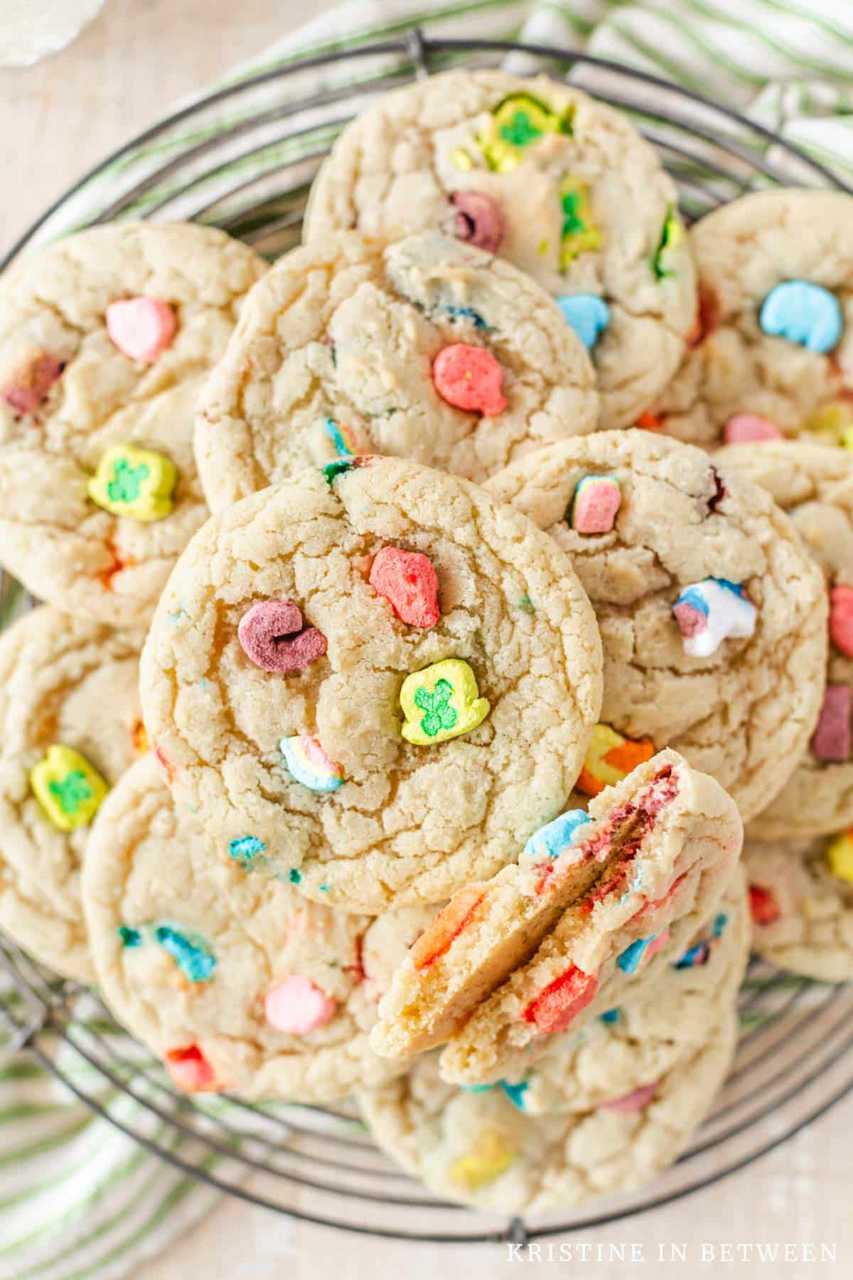 Lucky Charms cookies sitting on a round wire rack with a green striped napkin underneath.