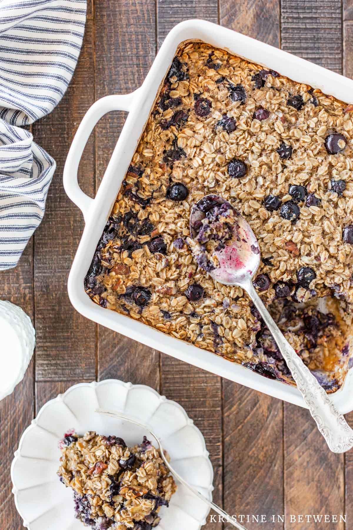 Baked blueberry pecan oatmeal in a casserole dish with a small plate next to it.