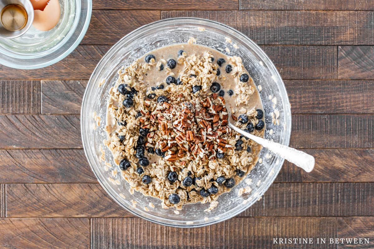 Pecans added to the blueberry oatmeal in a glass bowl.