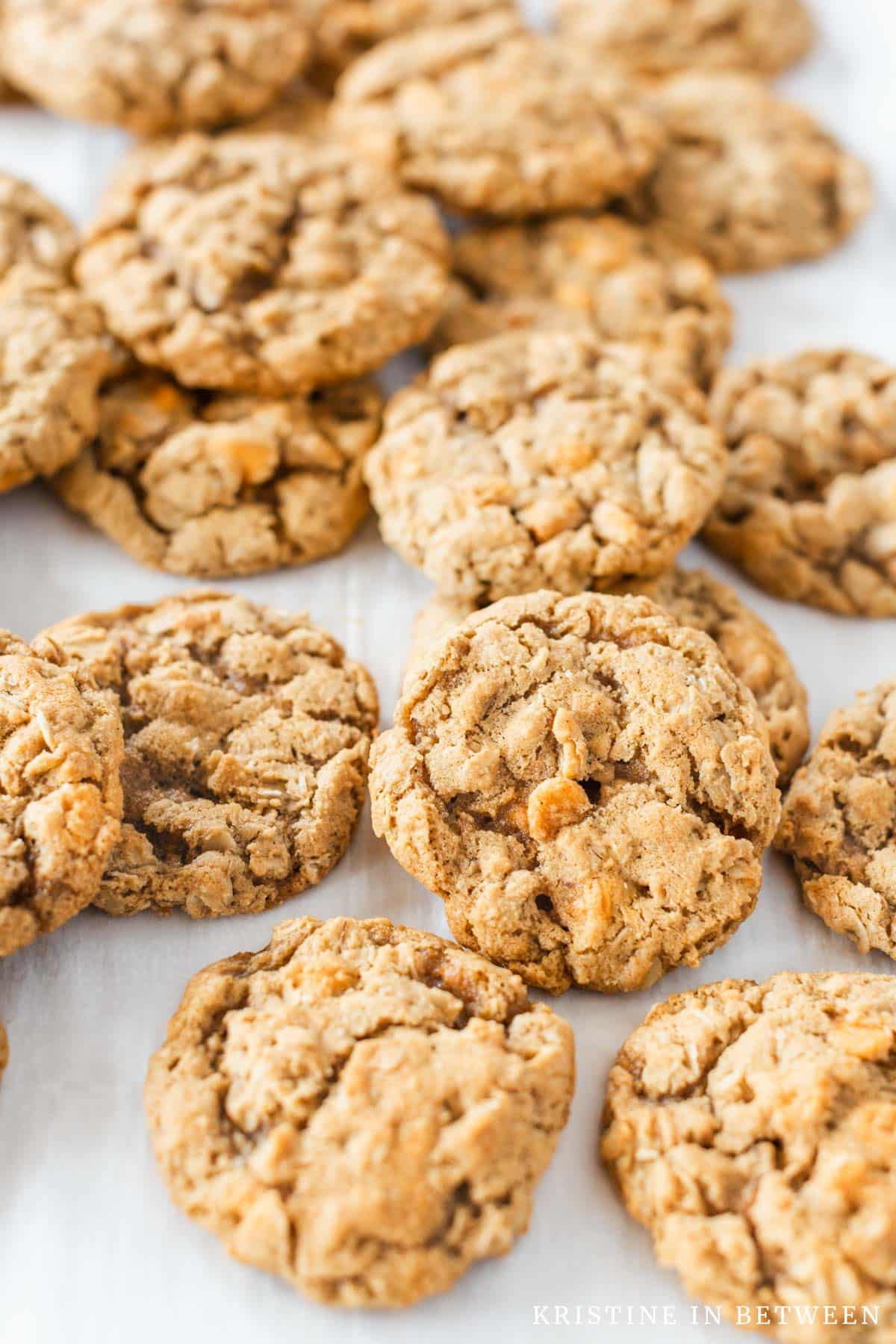 Oatmeal cookies laying on a baking sheet lined with parchment paper.