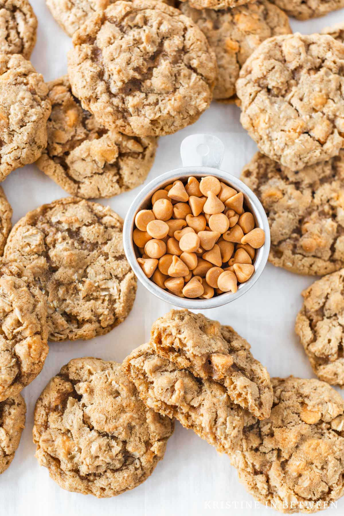 Butterscotch oatmeal cookies laying on a cookie sheet with a small bowl of butterscotch chips.