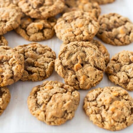 Butterscotch oatmeal cookies laying on a baking sheet with a blue napkin next to them.