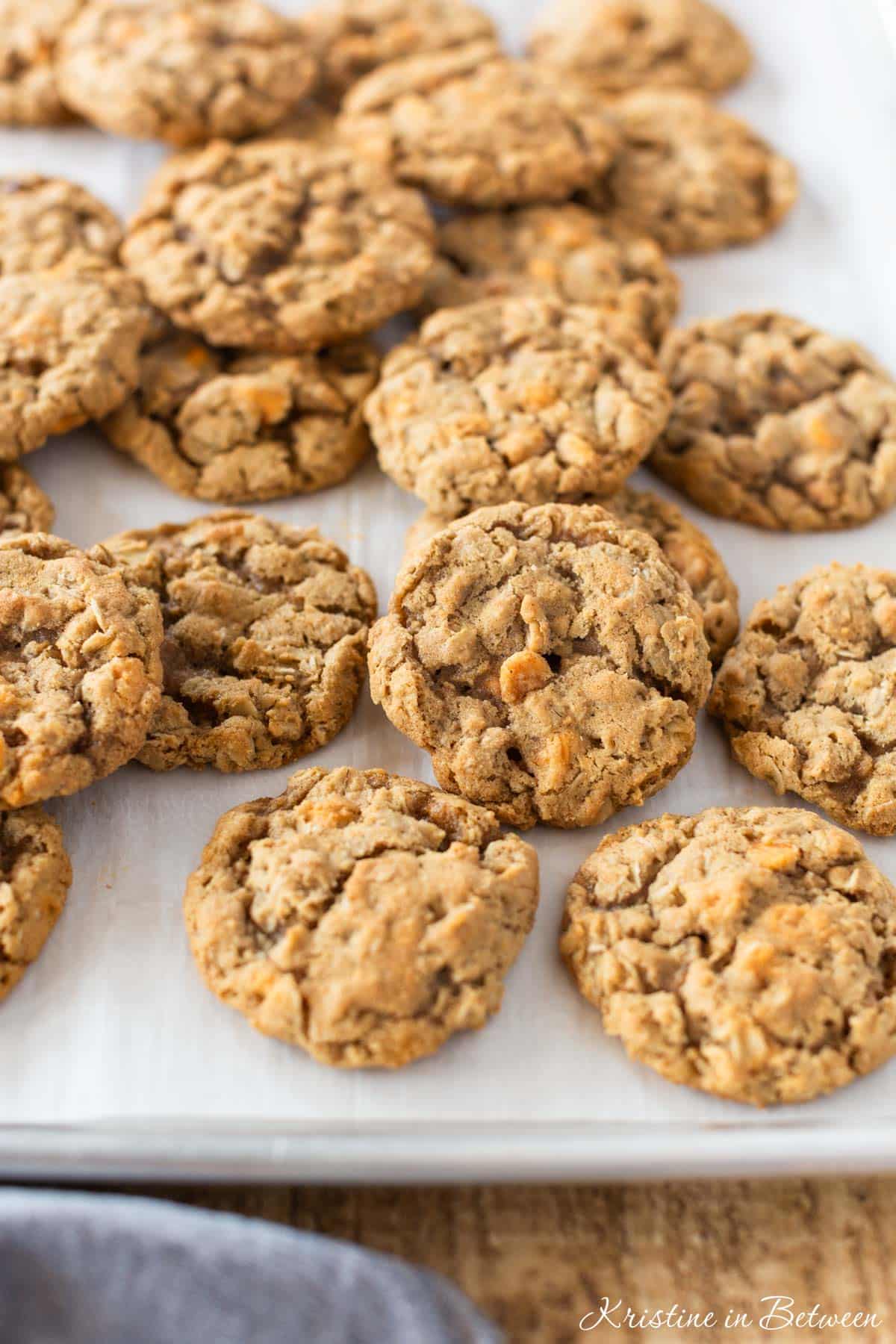 Butterscotch oatmeal cookies laying on a baking sheet with a blue napkin next to them.