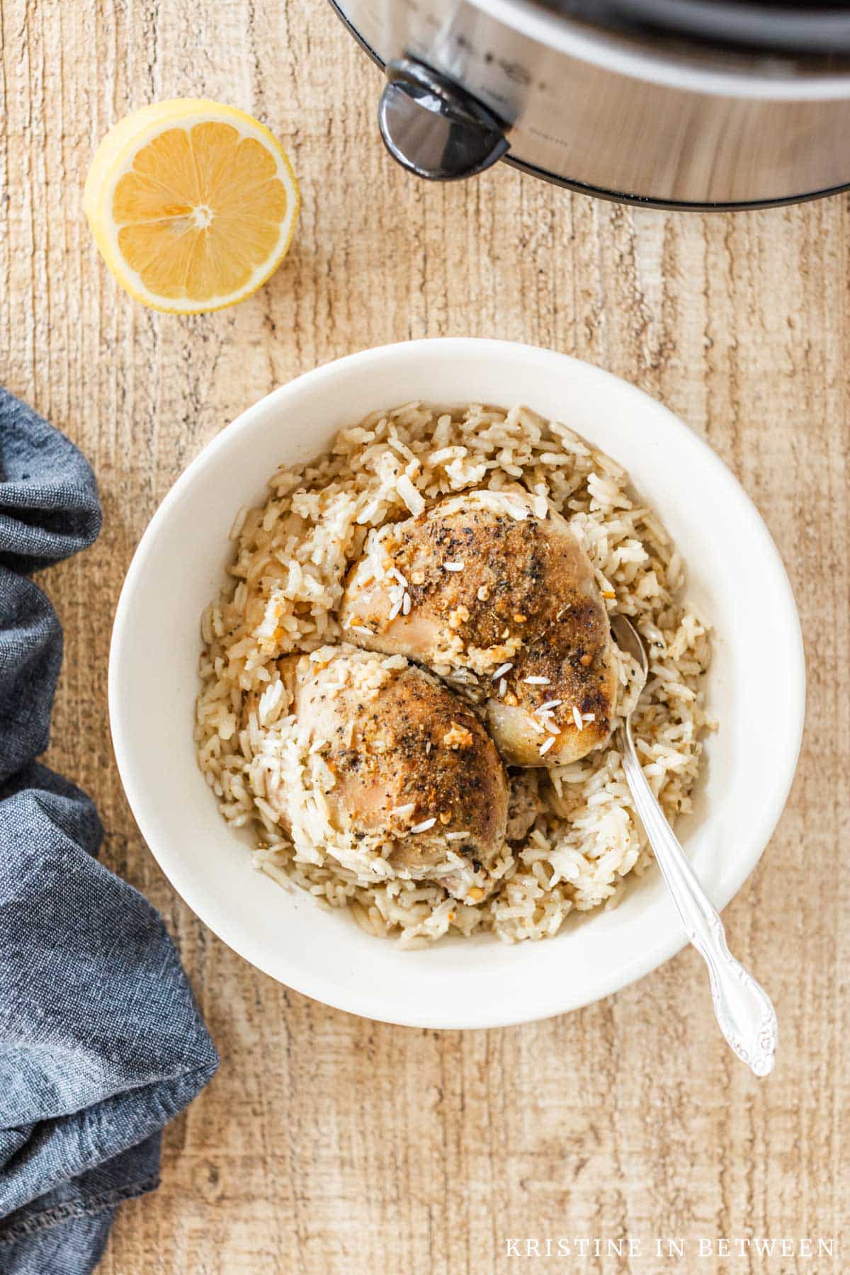 Two cooked chicken thighs with rice in a bowl with a fork.