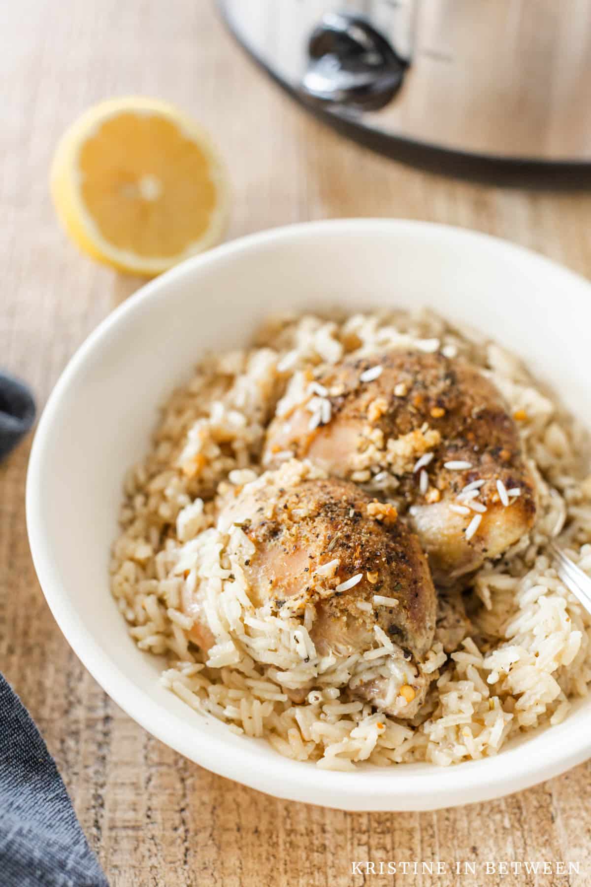Two chicken thighs in a bowl with rice and a fork.