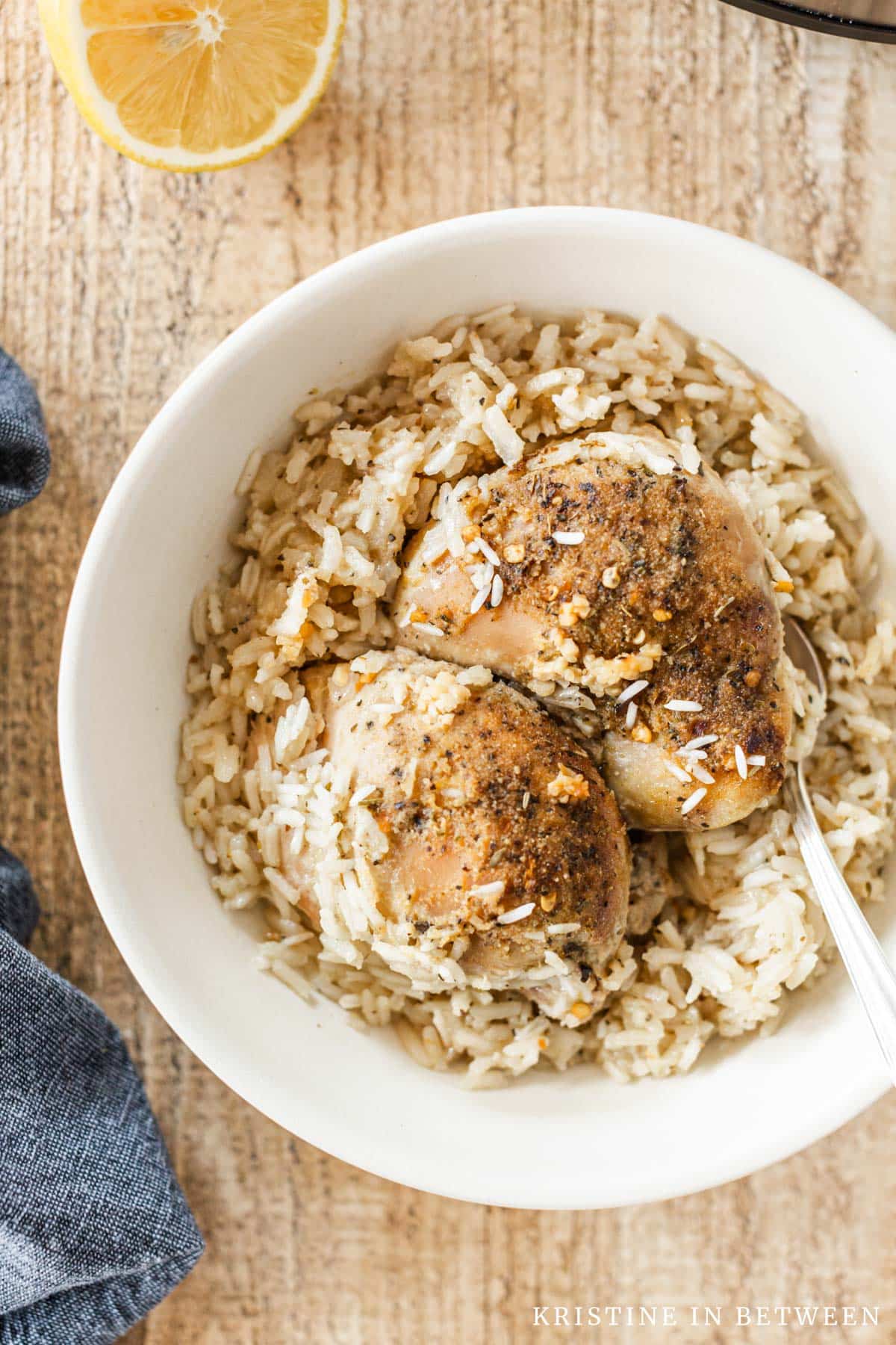 Two cooked chicken thighs with rice in a bowl.