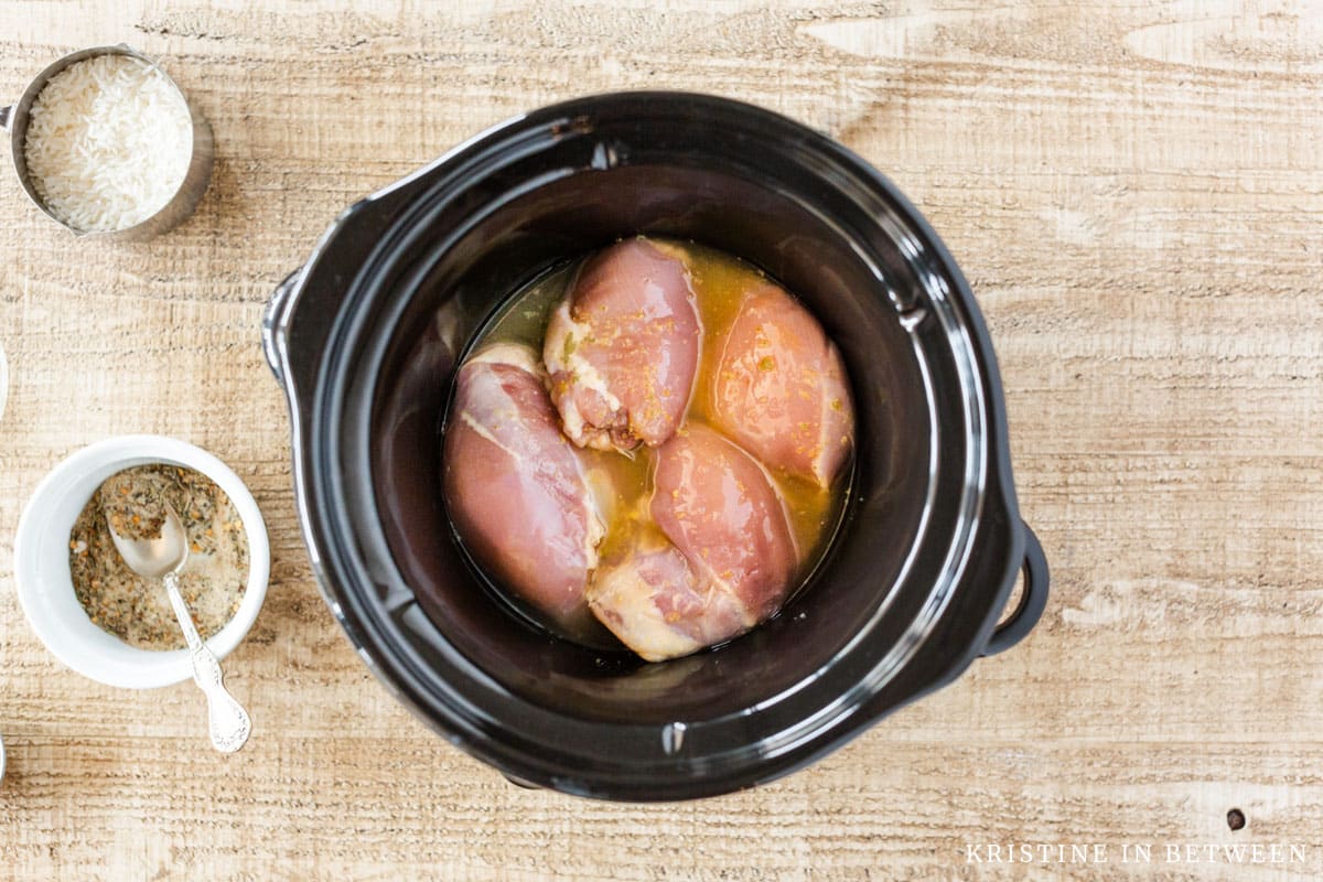 Lemon juice and chicken broth poured over chicken thighs in a crock pot.