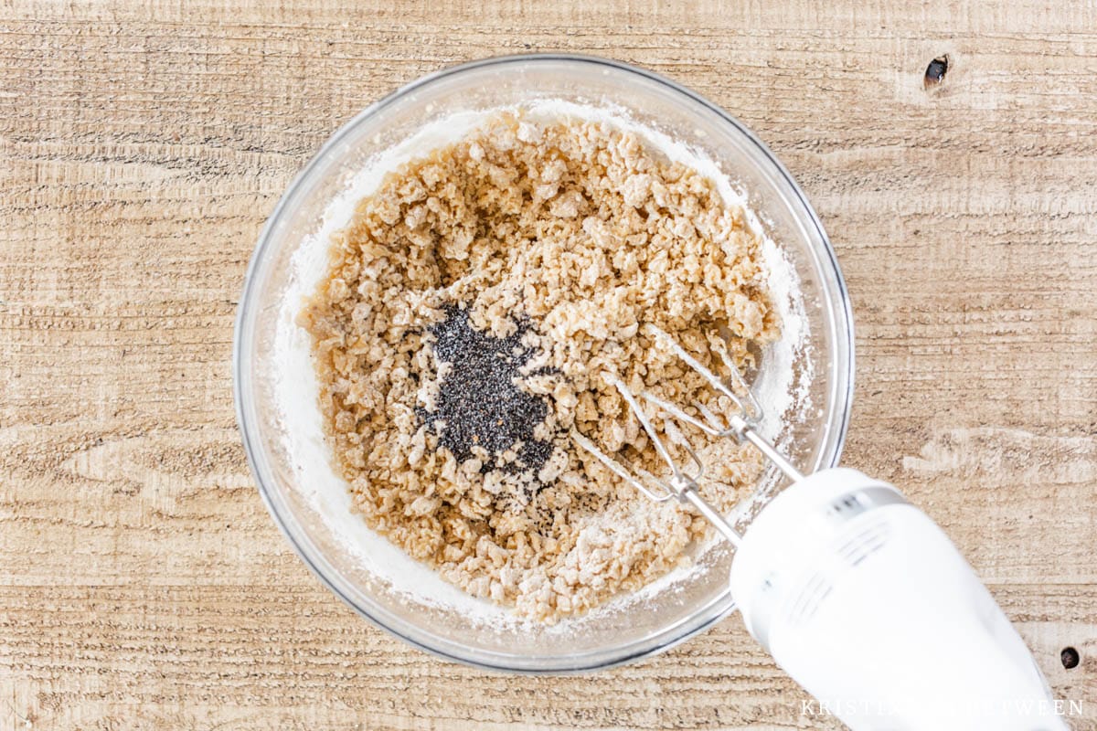 Poppy seeds added to a bowl of mixed cookie dough.