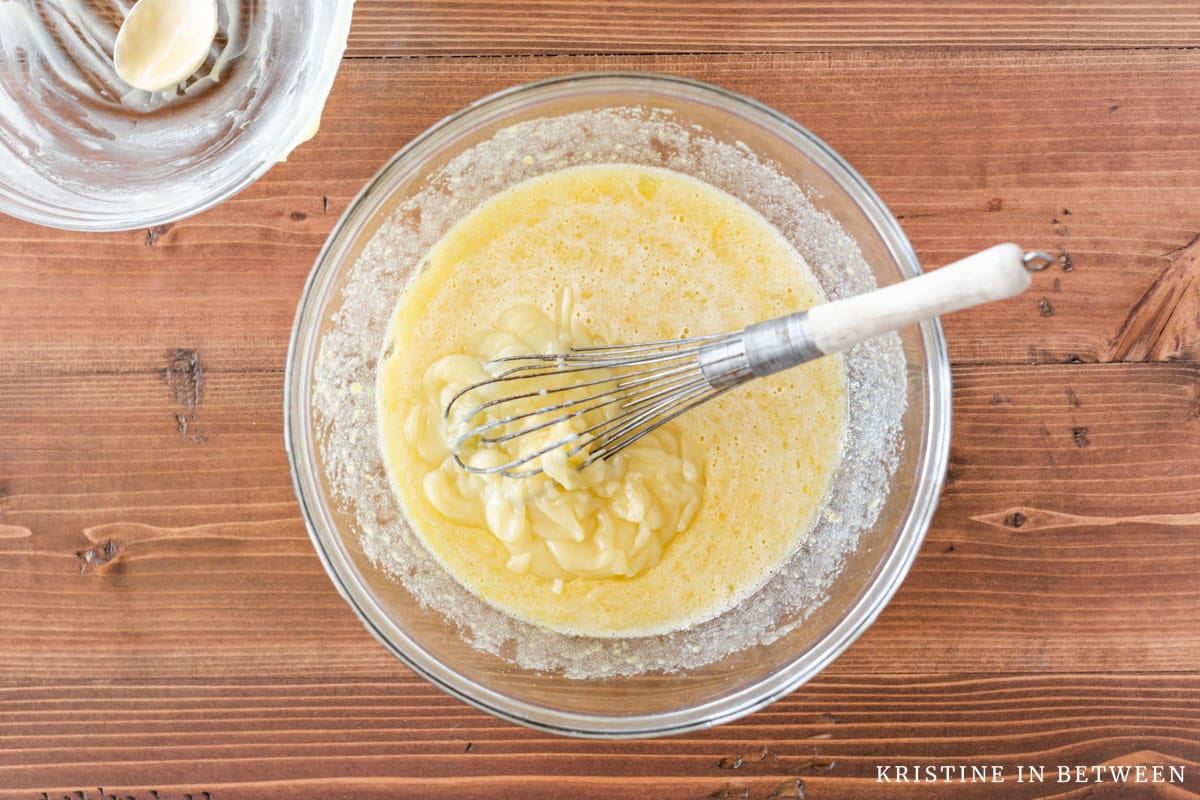 Melted butter added to the whisked sugar and eggs in a glass bowl.