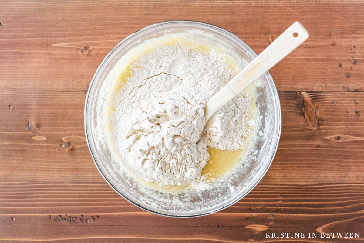 Flour on top of lemon brownie batter with a wooden spoon.