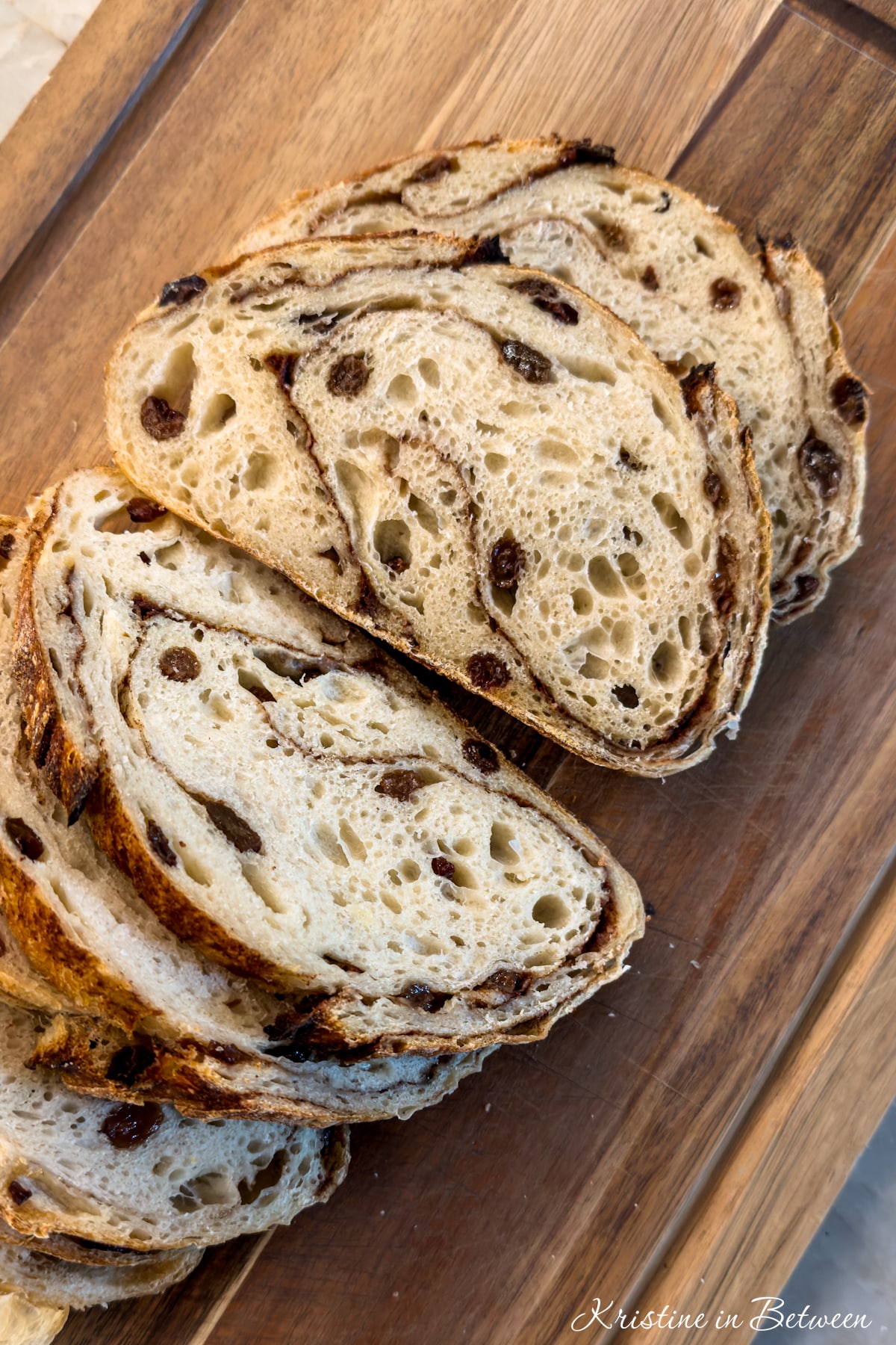 A loaf of cinnamon raisin sourdough sliced on a cutting board.