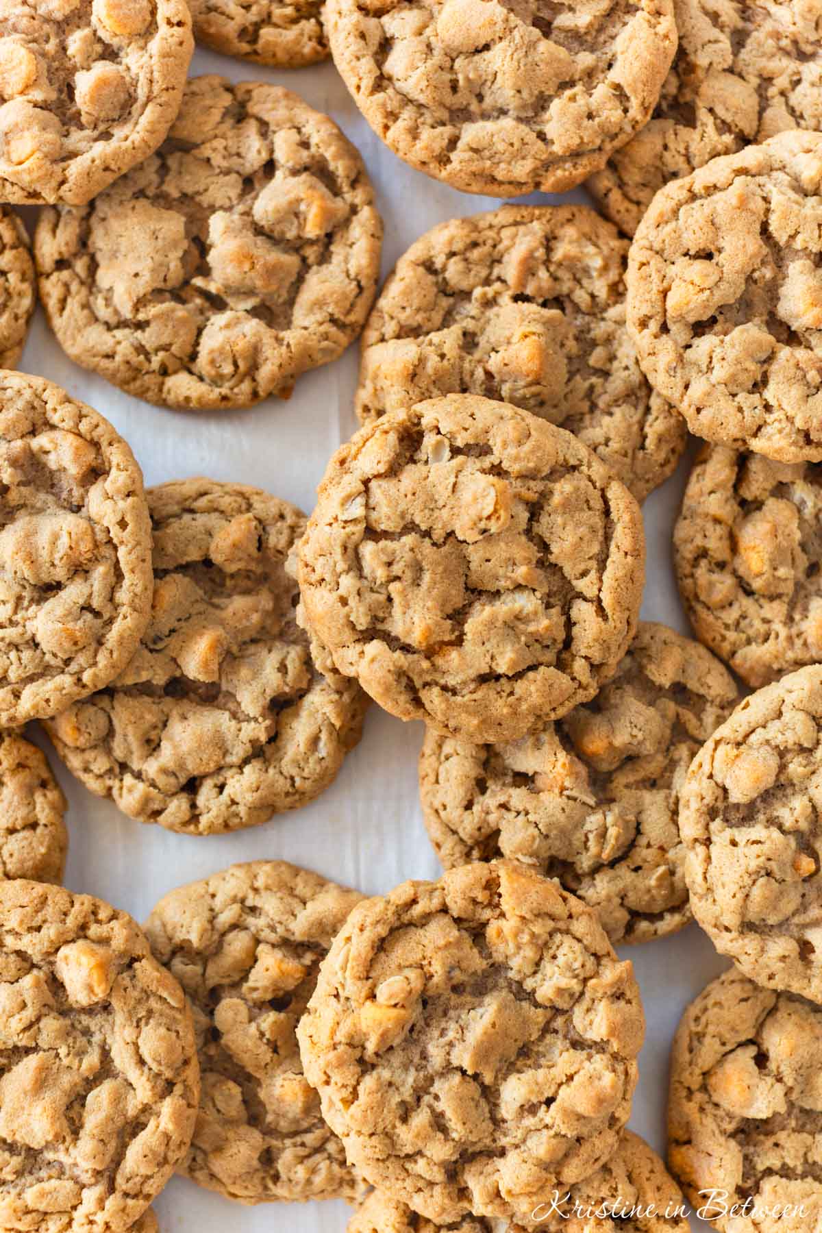 Peanut butter oatmeal butterscotch cookies laying on a baking sheet with a striped napkin next to them.
