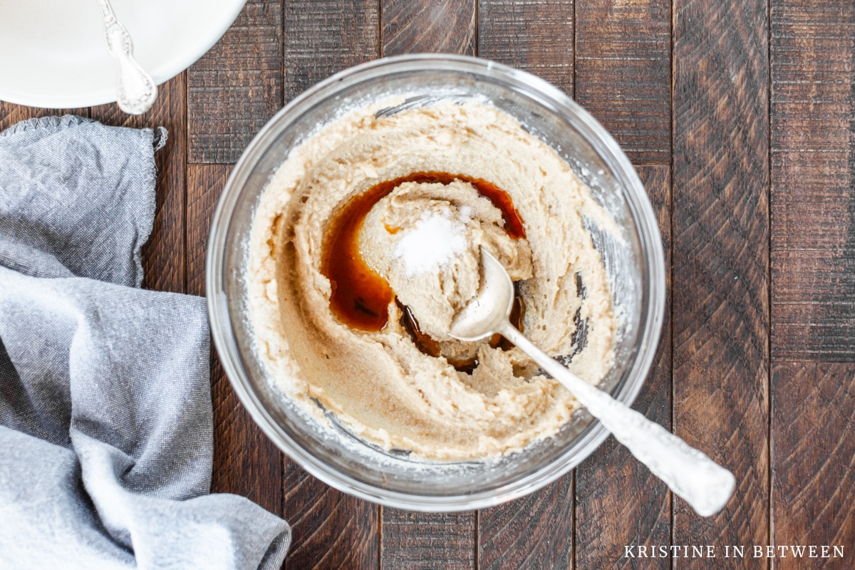 Vanilla extract and sea salt added to a bowl of creamed butter and sugar.