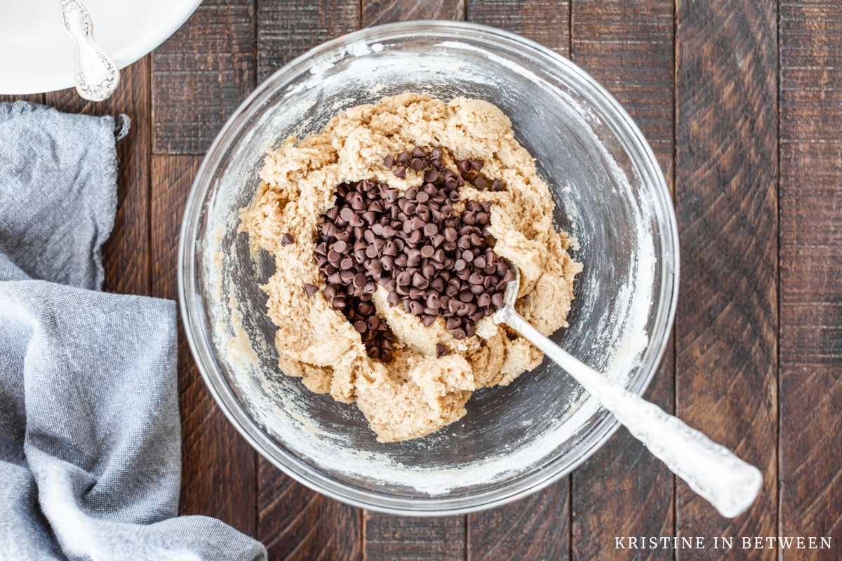 Chocolate chips added to a mixed bowl of cookie dough.