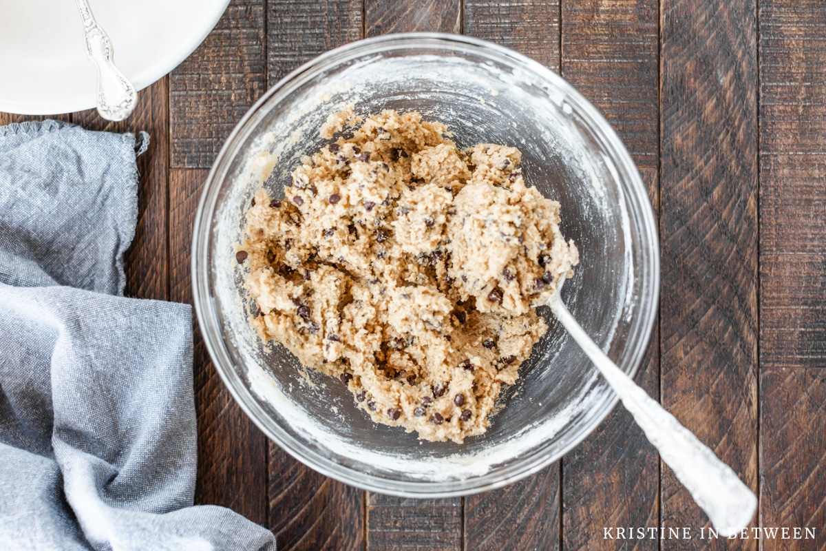 Edible cookie dough mixed up in a glass bowl with a spoon.