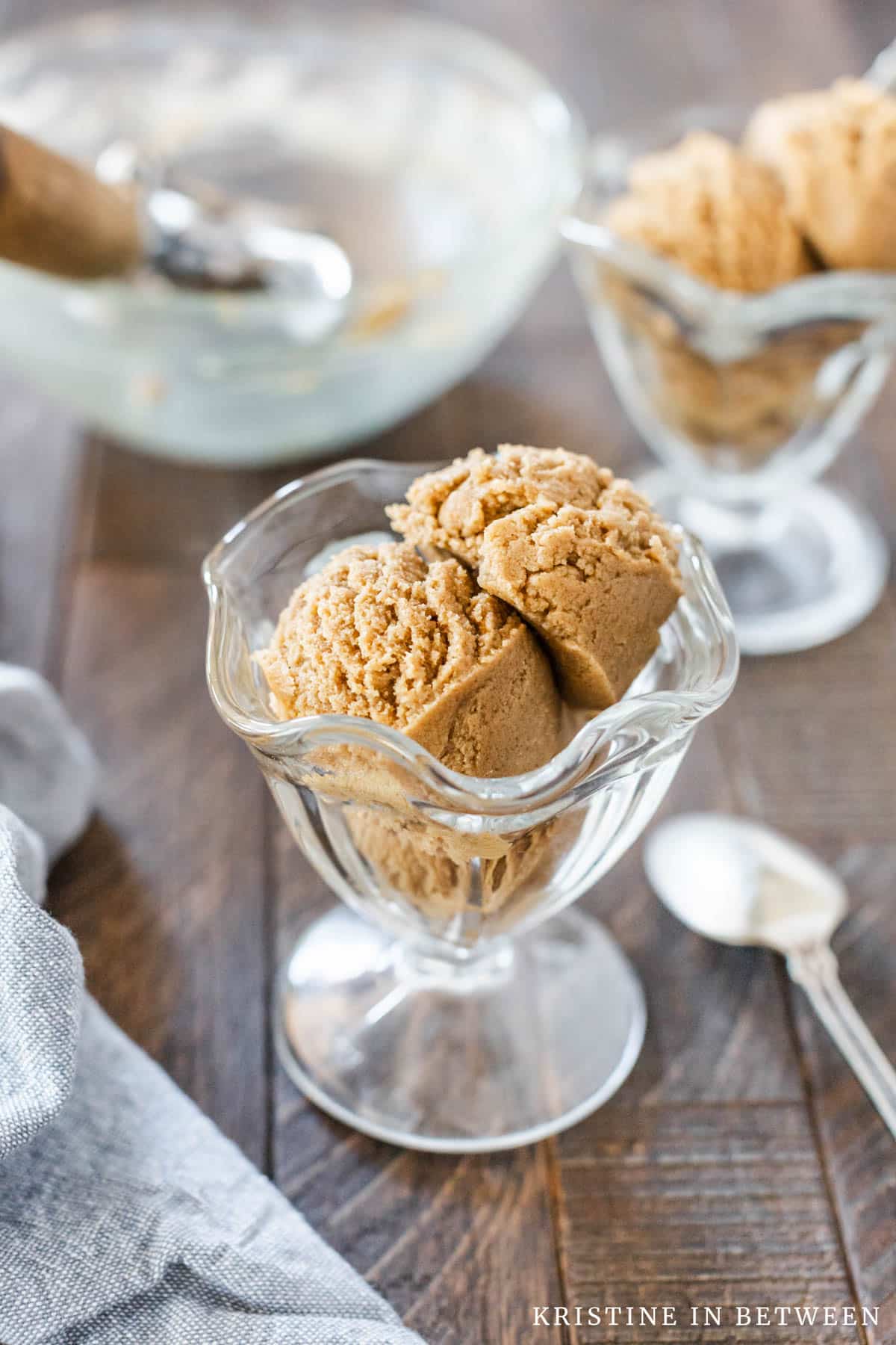 A sundae cup filled with edible peanut butter cookie dough with a spoon in it.