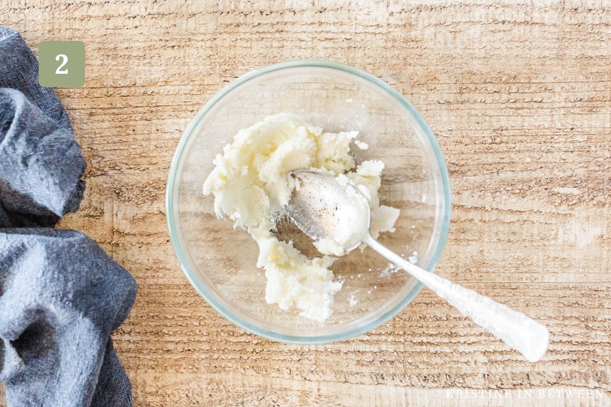 Butter and sugar creamed together in a glass bowl with an antique spoon.