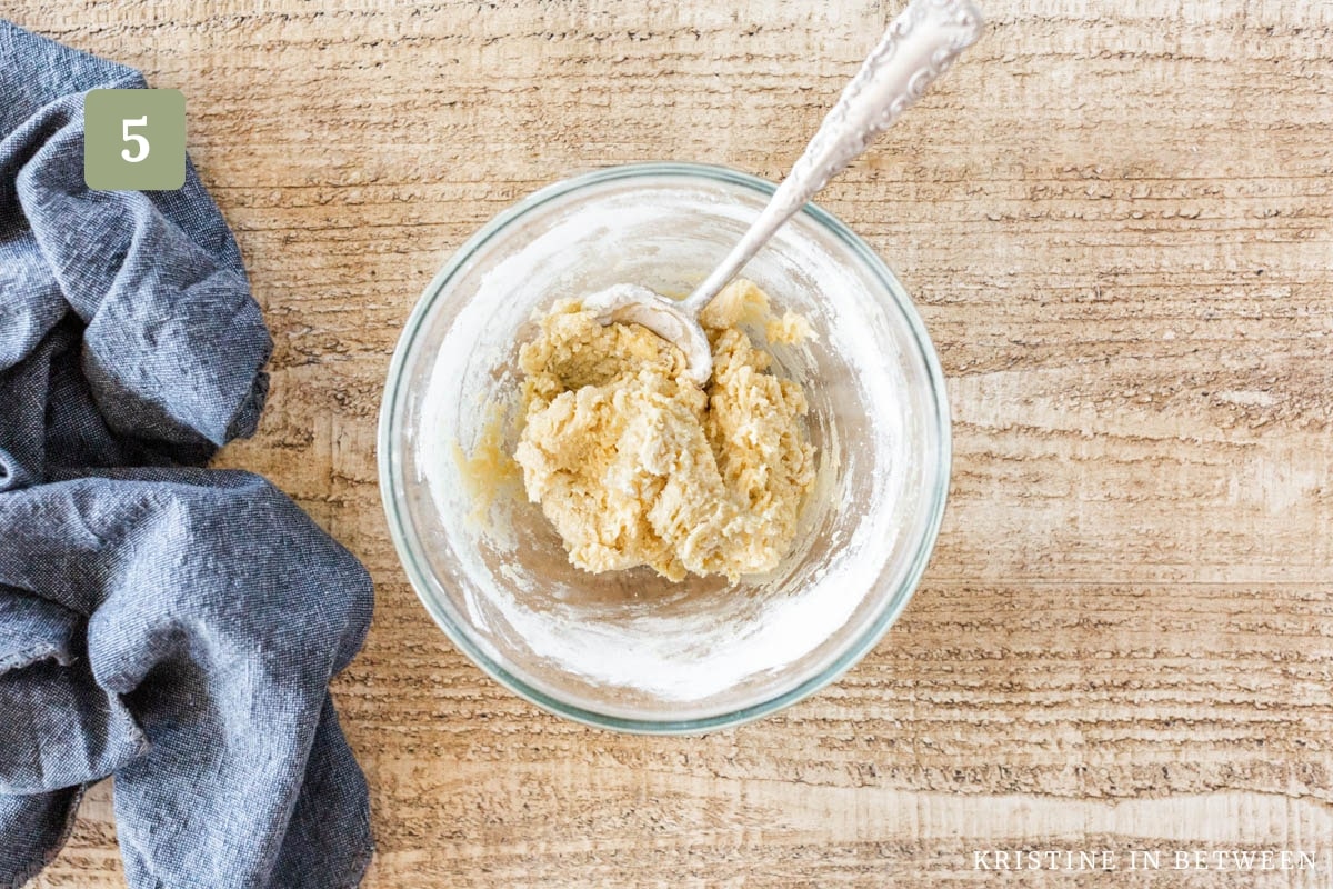 Raw cookie dough in a glass bowl with an antique spoon.