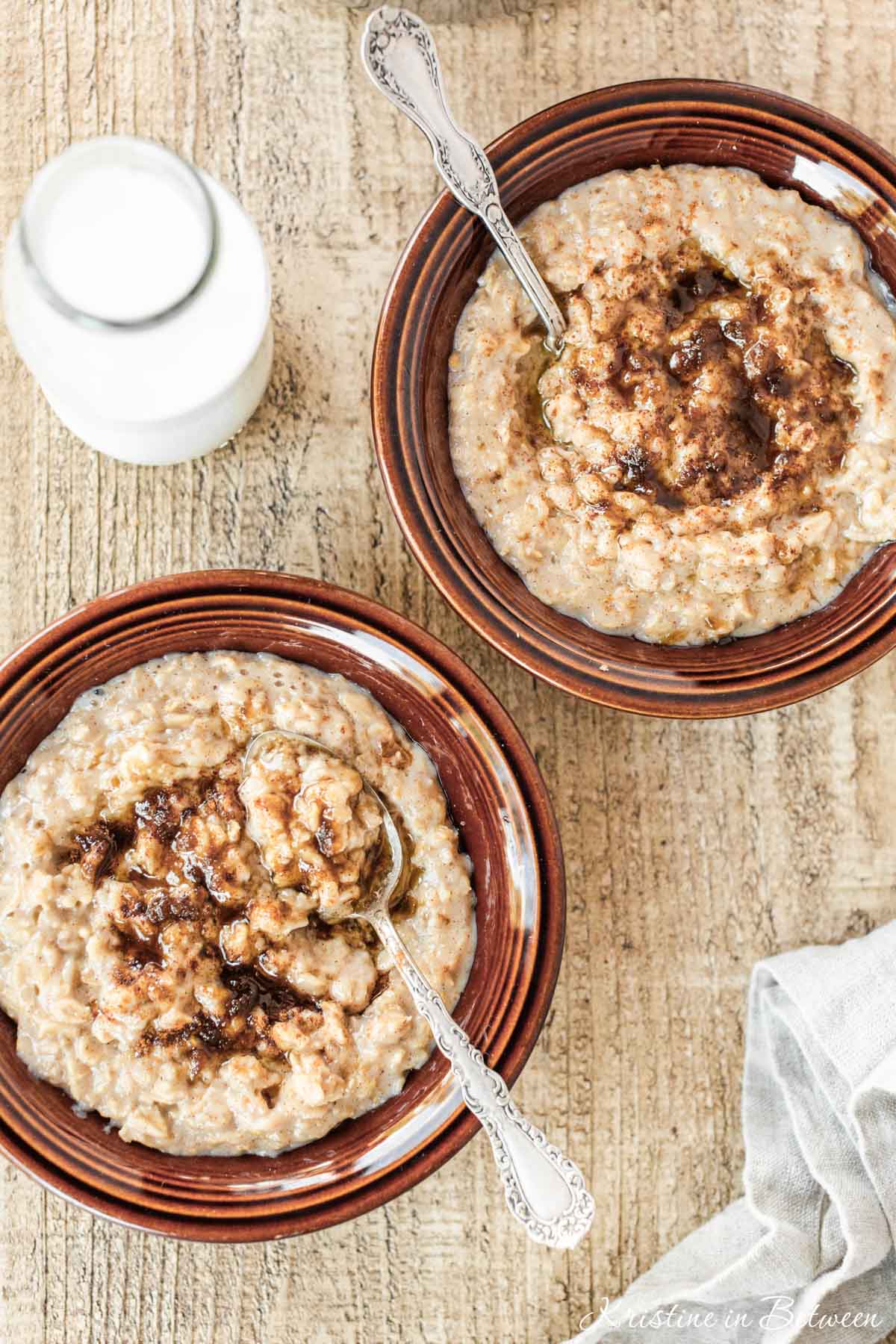 Two bowls of brown sugar cinnamon oatmeal with spoons, topped with brown sugar and cinnamon.