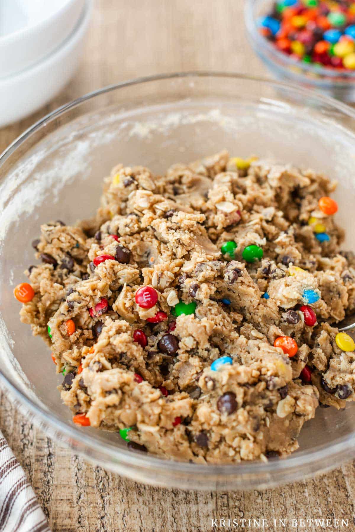 Edible cookie dough with chocolate chips and mini M&Ms in a glass bowl.