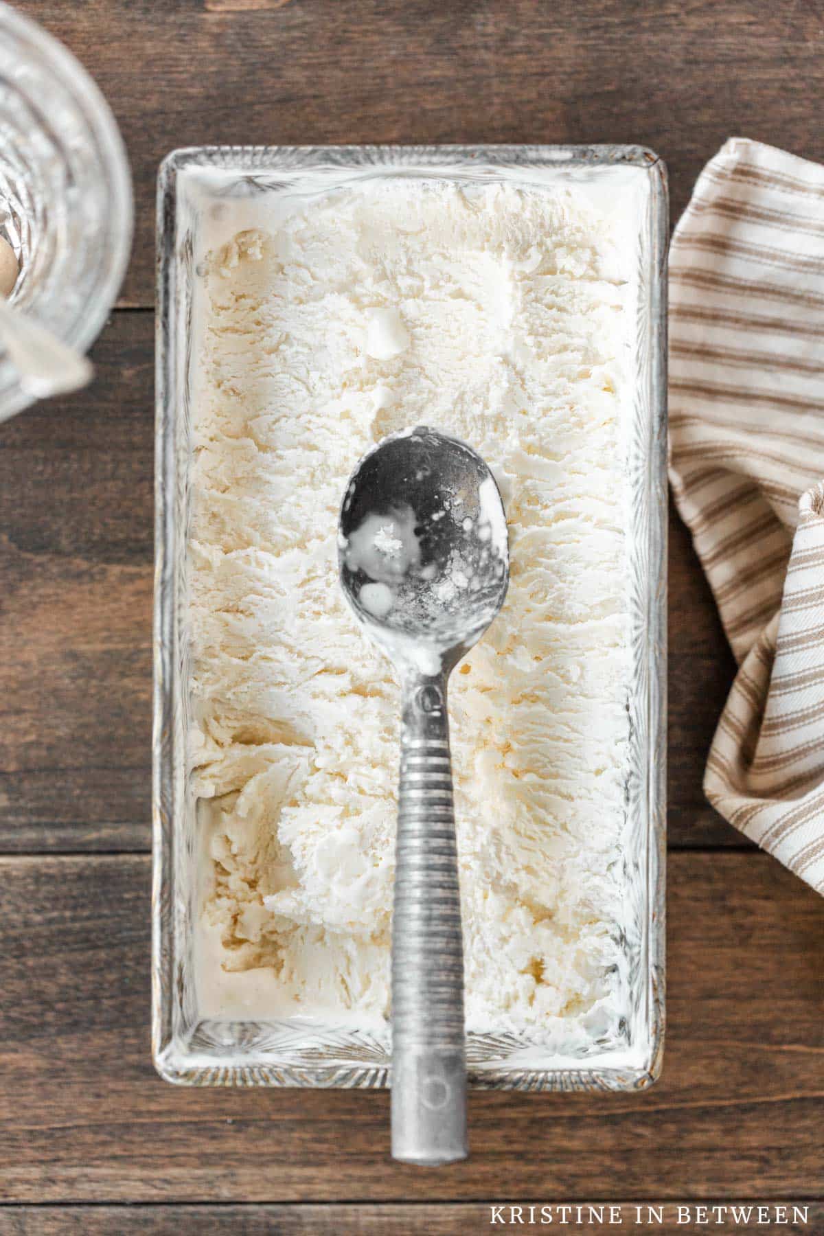 Vanilla no-churn ice cream in a loaf pan with a scoop on top.