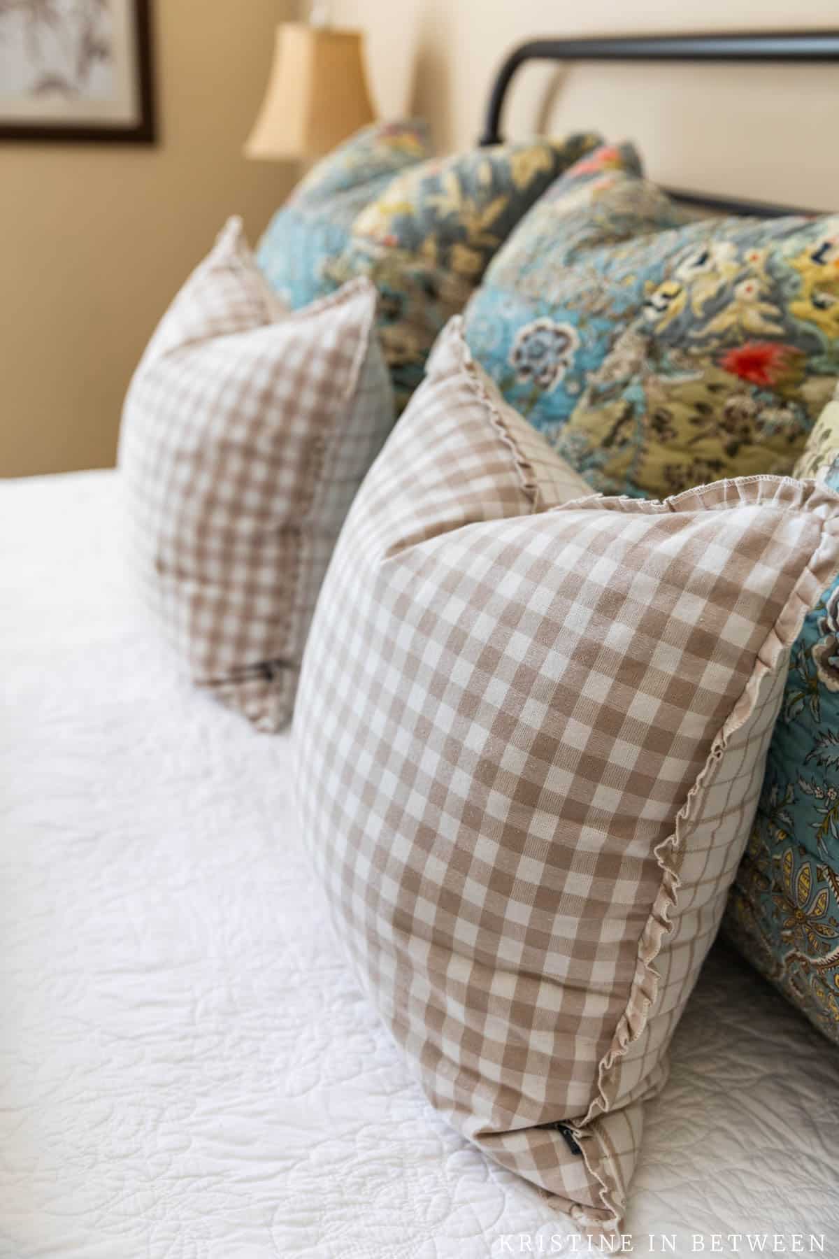 Freshly fluffed pillows sitting on a bed with a white quilt.