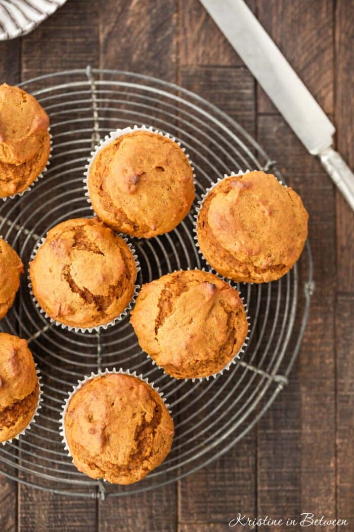 Pumpkin muffins sitting on a wire cooling rack with an antique knife next to them.