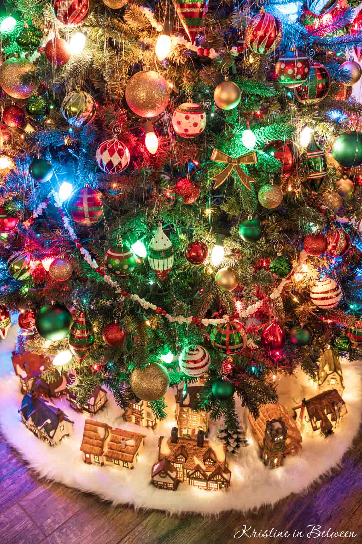 A Christmas village lit up under a traditional Christmas tree.