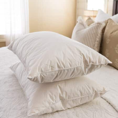 Two clean, stark white pillows sitting on a made bed.