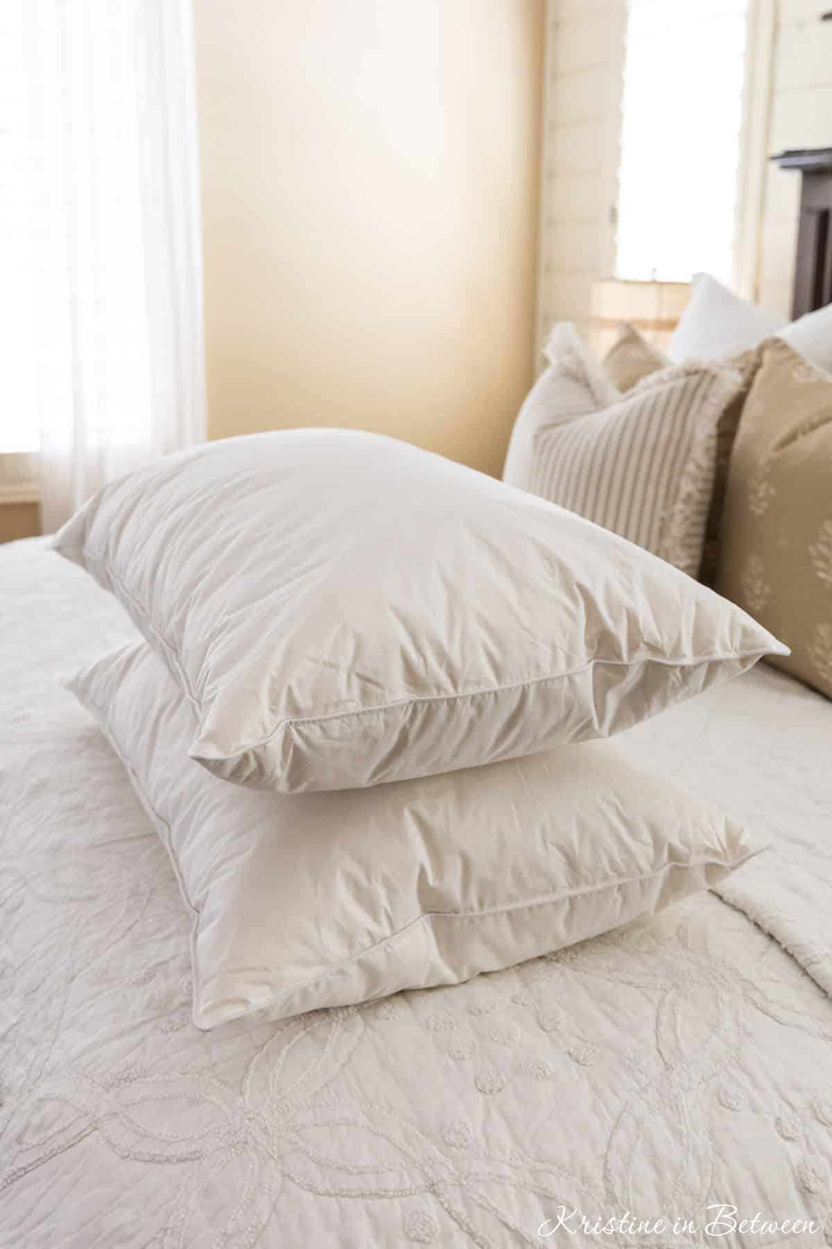Two clean, stark white pillows sitting on a made bed.