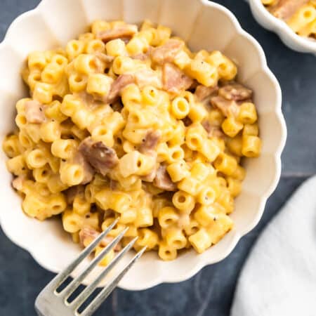 A bowl of homemade macaroni and cheese with a fork sitting next to it.