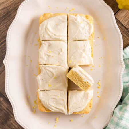 A plate of sliced lemon sugar cookie bars on a white plate, topped with lemon zest.