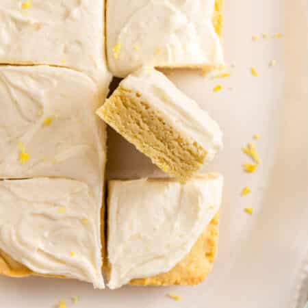 A plate of sliced lemon sugar cookie bars on a white plate, topped with lemon zest.