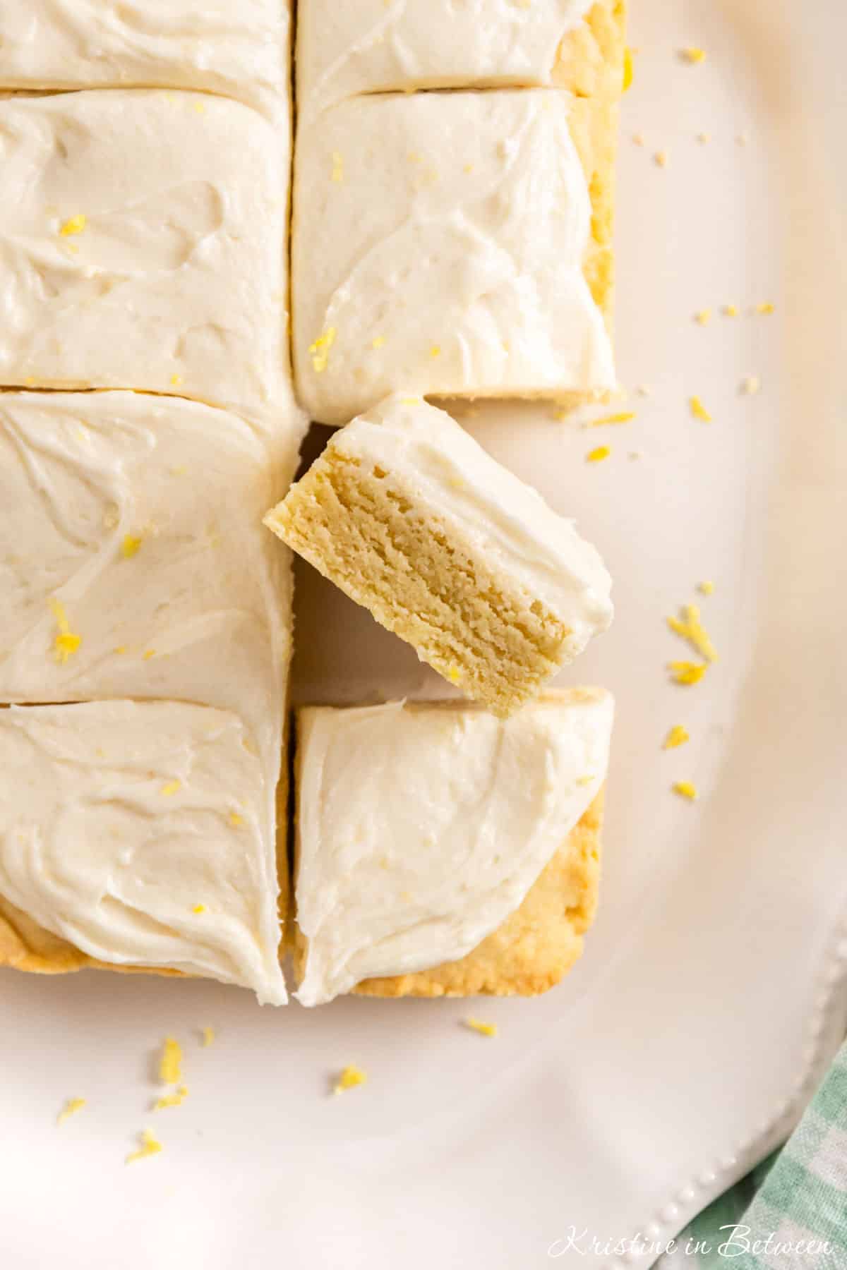 A plate of sliced lemon sugar cookie bars on a white plate, topped with lemon zest.