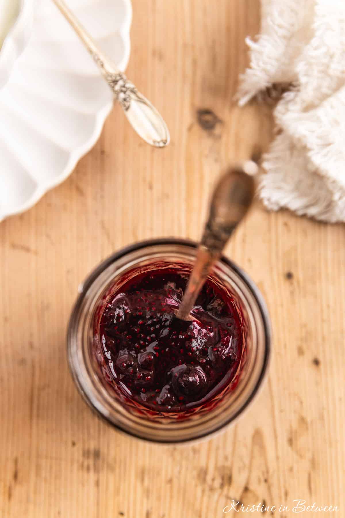 Homemade blueberry chia seed jam in a small mason jar with a spoon.