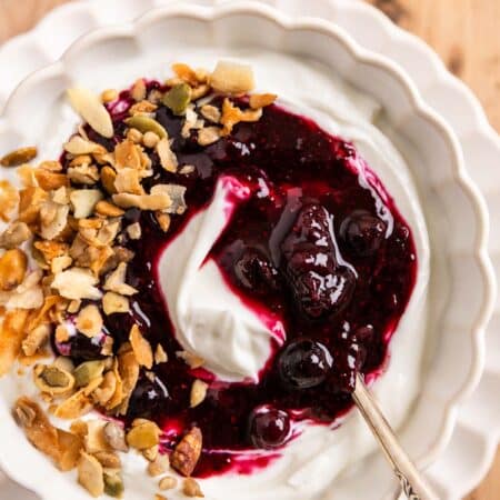 Blueberry chia jam over some yogurt in a white bowl with a spoon.