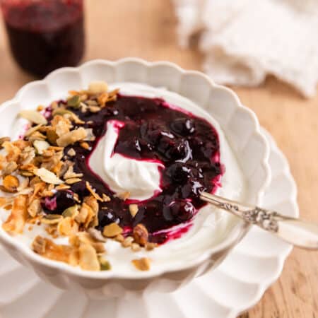 Blueberry chia jam over some yogurt in a white bowl with a spoon.