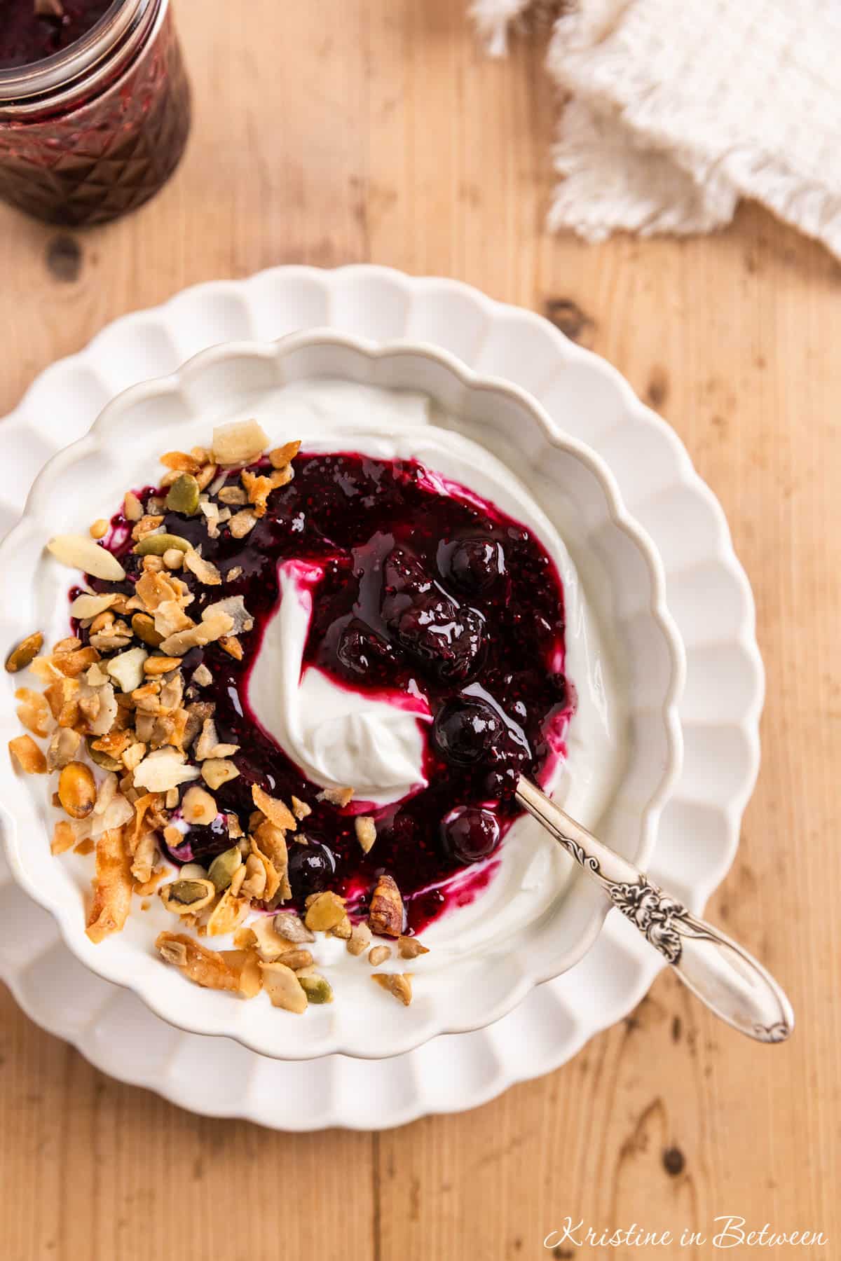 Blueberry chia jam over some yogurt in a white bowl with a spoon.