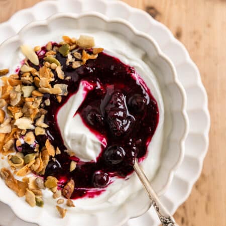 Blueberry chia jam over some yogurt in a white bowl with a spoon.