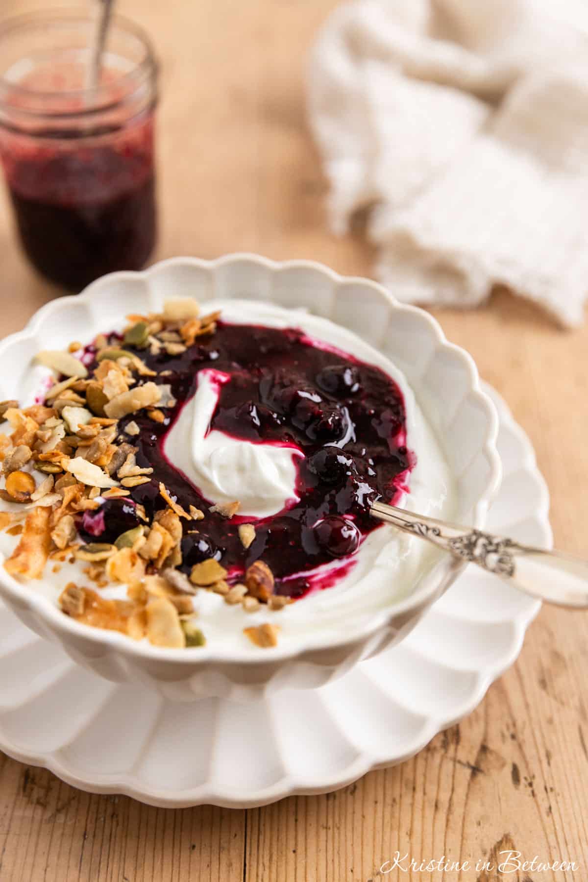 Blueberry chia jam over some yogurt in a white bowl with a spoon.