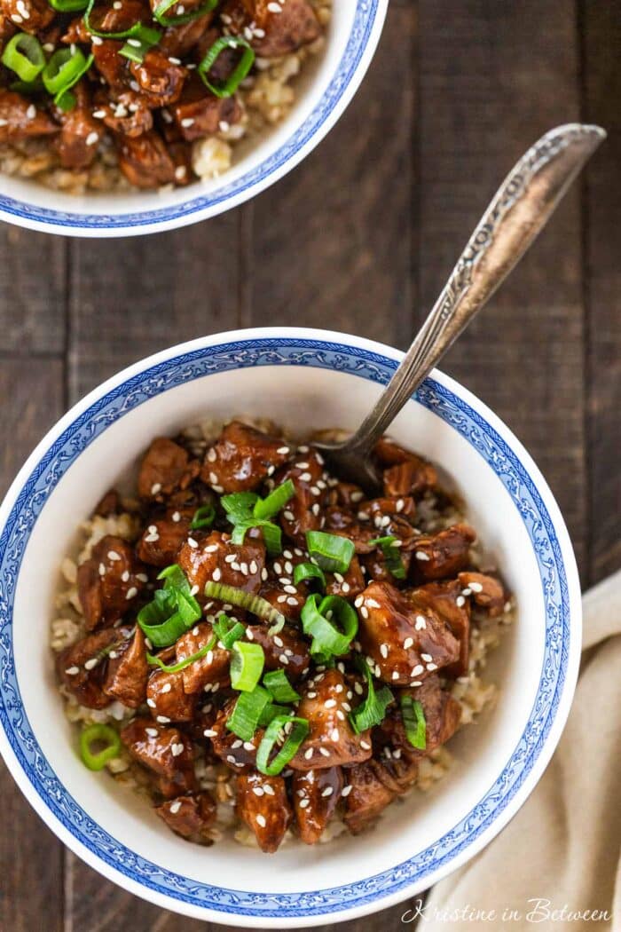 A bowl of teriyaki chicken with a fork in it.