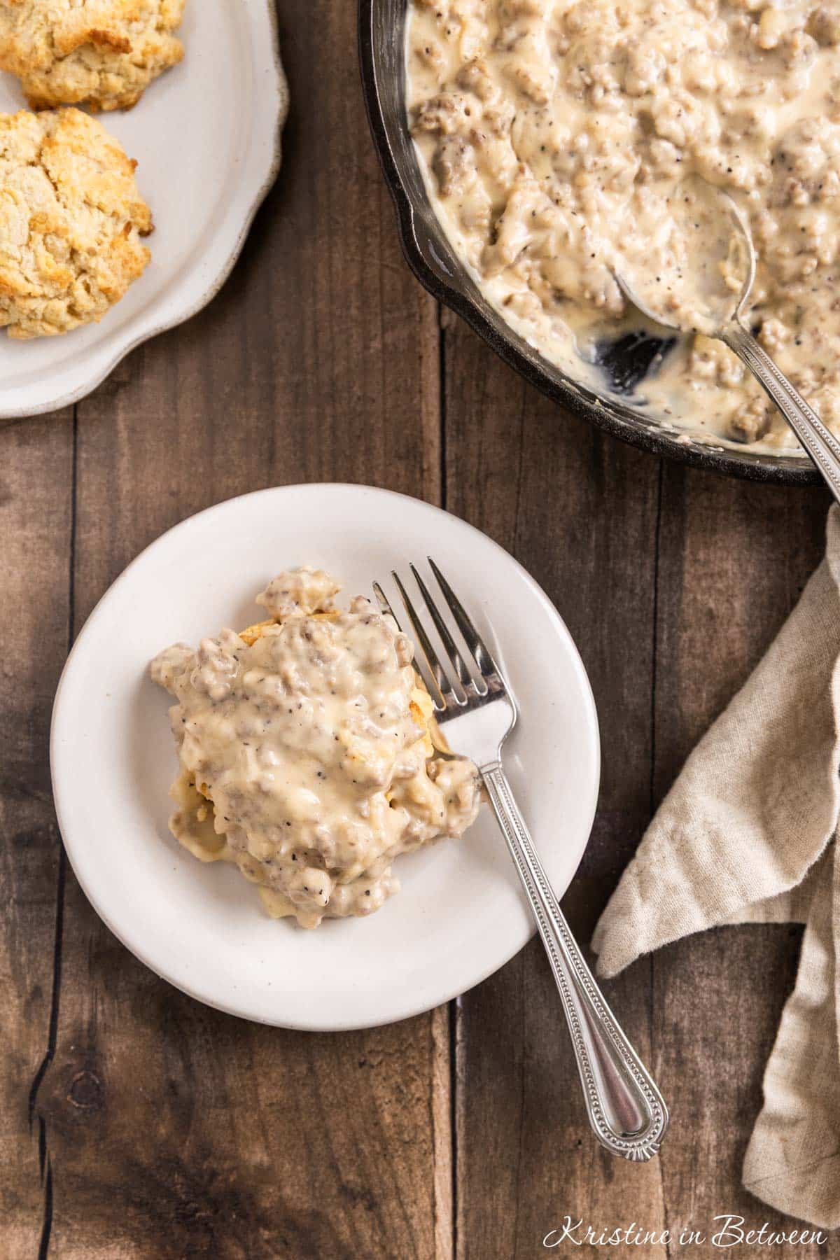 A small plate of biscuits and gravy with a fork sitting with it.
