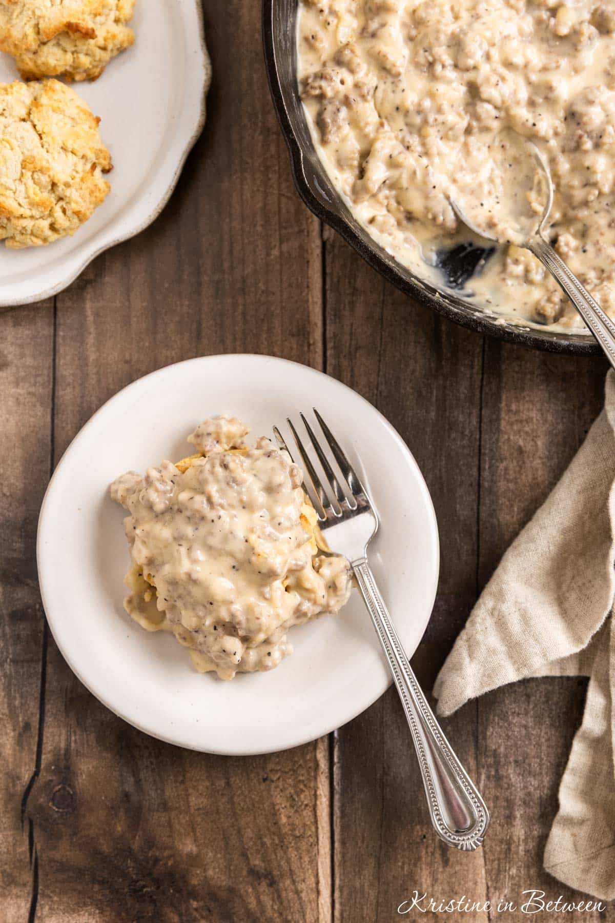 A small plate of biscuits and gravy with a fork sitting with it.