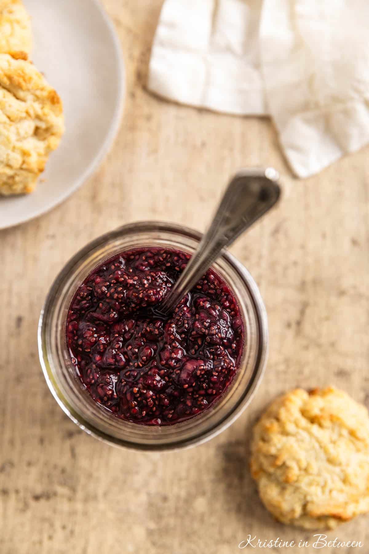 Looking into a jar of raspberry jam with a spoon in it.