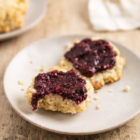A biscuit cut in half with raspberry chia seed jam spread over the top.